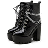 Black patent leather ankle boot with platform heel, laceup, and draped chain accent 